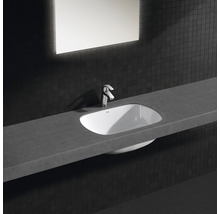 Lavabo dans une salle de bain avec robinet, miroir et carreaux sombres.