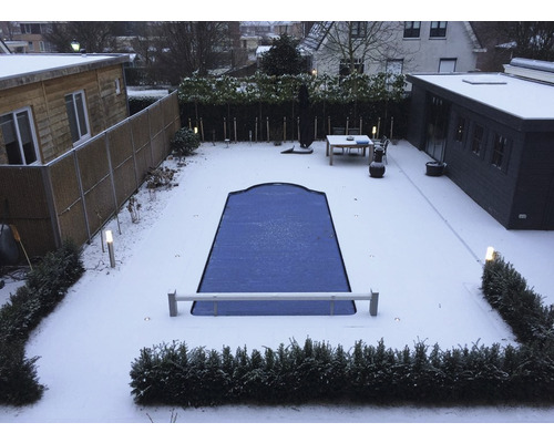 Schneebedeckter Garten mit abgedecktem Pool, Gartenhaus und Terrasse.