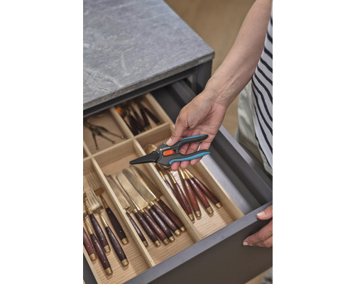 Une personne prend une cisaille à fleurs Gardena dans un tiroir à couverts.