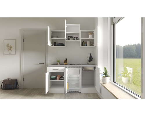 Kompakte Küchenzeile mit Spüle, Kochfeld, Kühlschrank und Hängeschränken in einer hellen Raumszene.