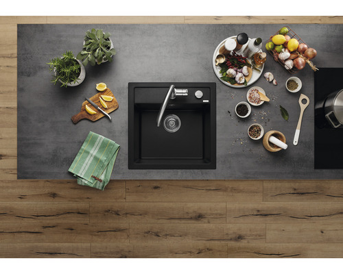 Küchenszene mit Spüle, Armatur, Kräutern, Gewürzen und Lebensmitteln auf einer Arbeitsplatte