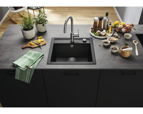 Schwarzes Küchenspülbecken mit Armatur und diversen Küchenutensilien auf einer Arbeitsplatte