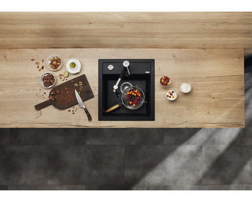 Scène de cuisine avec évier, robinet, planche à découper, fruits et ingrédients sur un plan de travail