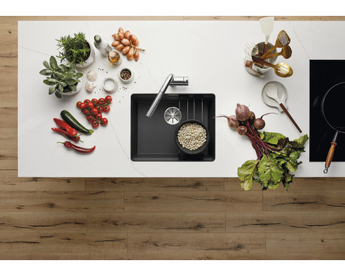 Évier de cuisine avec robinet sur un comptoir de cuisine avec des légumes et des ustensiles de cuisine