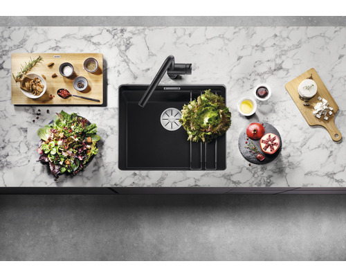 Évier de cuisine avec robinet, planche à découper et ingrédients sur un plan de travail.