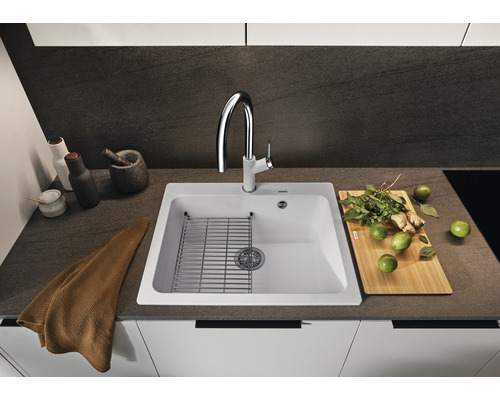 Évier de cuisine avec égouttoir, robinet et divers ustensiles de cuisine sur un plan de travail