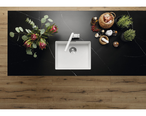 Évier de cuisine dans un plan de travail avec robinetterie, herbes et épices