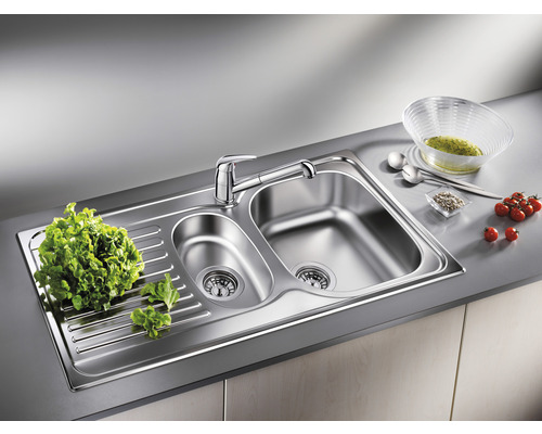 Évier en acier inoxydable avec égouttoir et robinet sur un plan de travail de cuisine.