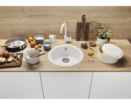 Scène de cuisine avec un évier rond, un robinet et des ingrédients de pâtisserie sur un plan de travail