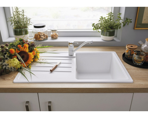 Évier de cuisine avec égouttoir et mitigeur monocommande devant une fenêtre de cuisine décorée