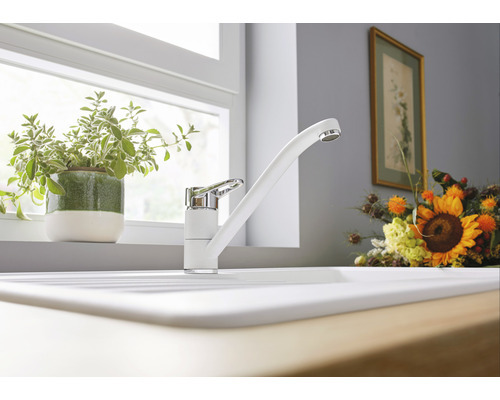 Évier de cuisine avec robinet blanc devant une fenêtre