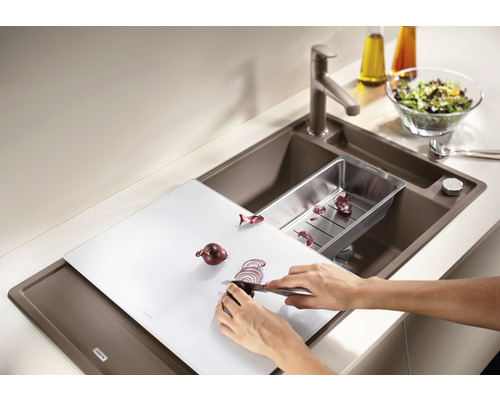 Évier avec planche à découper, égouttoir, robinet et personne coupant des oignons