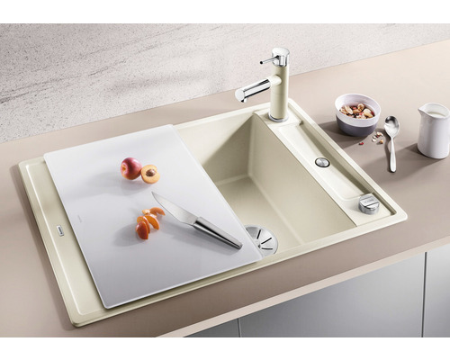 Küchenspüle mit Armatur, Schneidebrett, Messer und Obst.