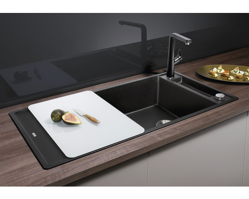 Schwarze Küchenspüle mit Schneidebrett, Wasserhahn und Spülmittelspender auf einer Arbeitsplatte