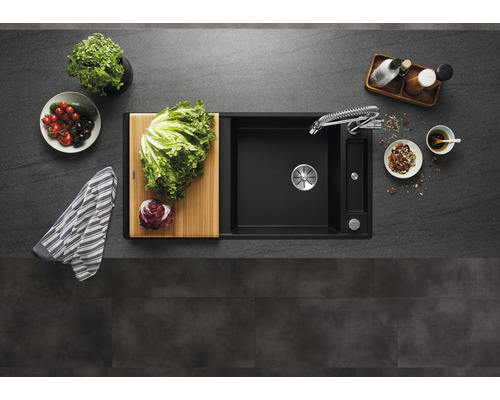 Évier avec égouttoir, robinetterie et planche à découper sur un plan de travail de cuisine.