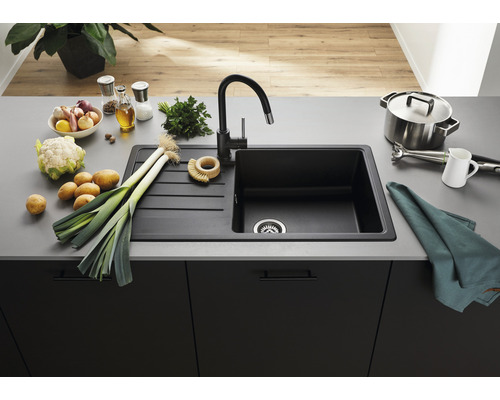 Küchenszene mit Spüle, Armatur und verschiedenen Lebensmitteln auf einer Arbeitsplatte