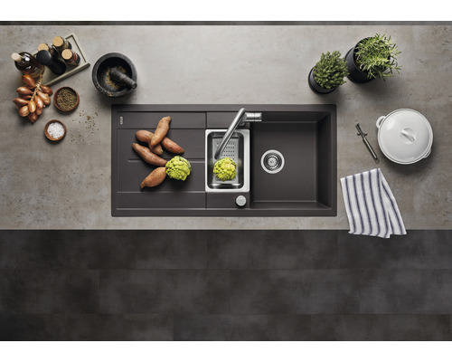 Küchenspüle mit Abtropffläche, Armatur, Gemüseschneider und Zutaten auf einer Arbeitsplatte.