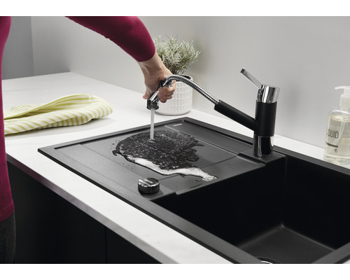 Schwarzes Küchenspülbecken mit Wasserhahn und Brausefunktion in einer hellen Küche
