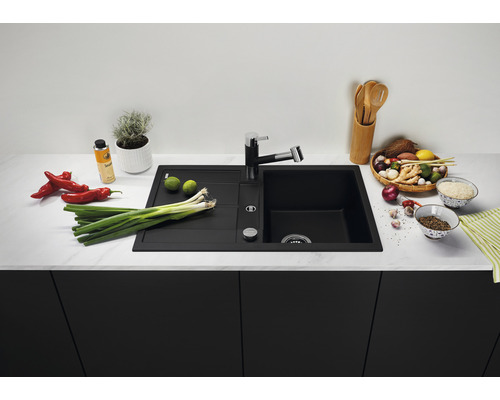 Schwarzes Spülbecken mit Armatur auf einer Küchentheke mit Lebensmitteln