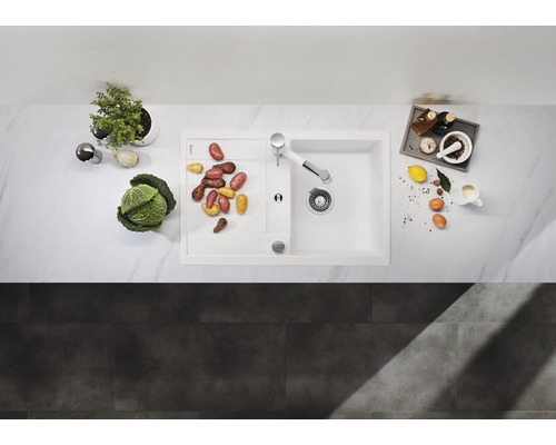 Küchenspüle mit Abtropffläche, Armatur und diversen Küchenutensilien auf einer Arbeitsfläche