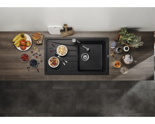 Aufnahme von oben einer modernen, schwarzen Küchenspüle mit Frühstückszutaten auf einer hölzernen Arbeitsplatte