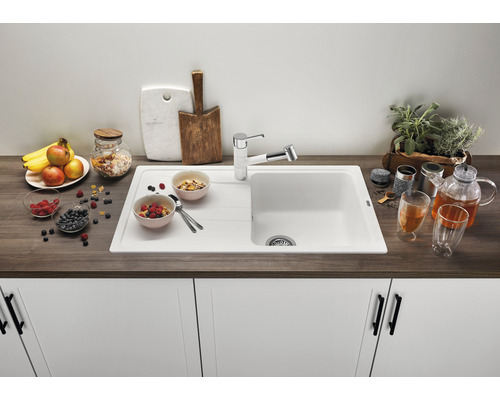 Küchenspüle mit Abtropffläche, Armatur und dekorativen Lebensmitteln auf einer Küchentheke