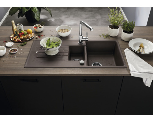 Küchenspüle mit Abtropffläche, Armatur und verschiedenen Küchenutensilien auf einer Küchentheke