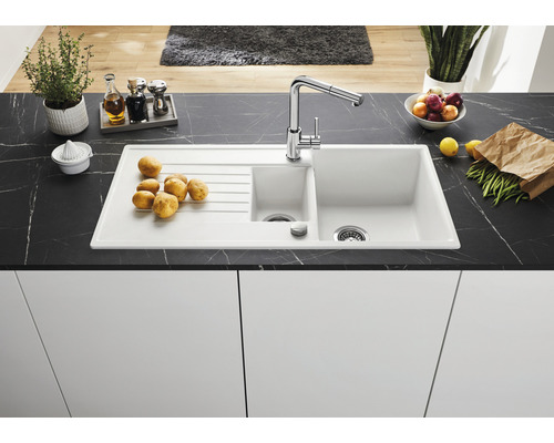 Küchenspüle mit Abtropffläche, Einhebelmischer und verschiedenen Lebensmitteln auf einer Arbeitsplatte