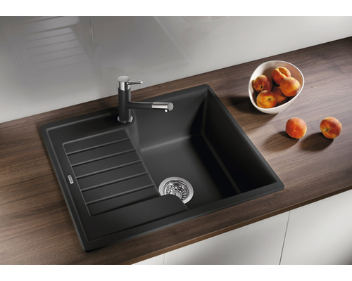 Schwarze Küchenspüle mit Abtropffläche und Armatur auf einer Arbeitsplatte.