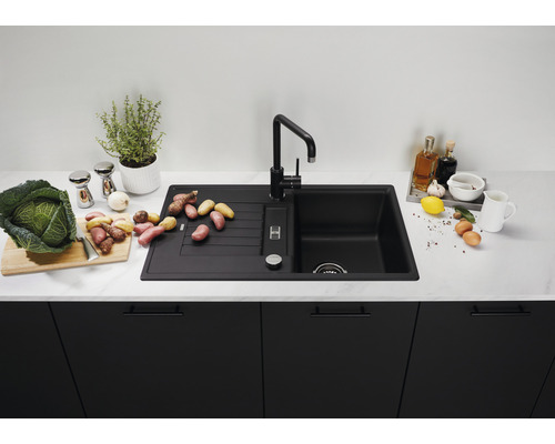 Évier de cuisine noir avec égouttoir et robinet sur un comptoir de cuisine avec des aliments
