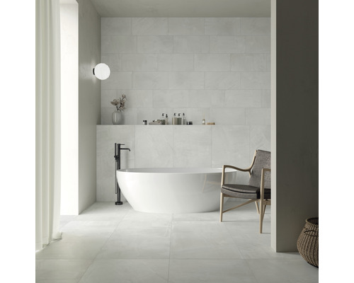 Salle de bains lumineuse avec baignoire îlot, fauteuils et carrelage mural