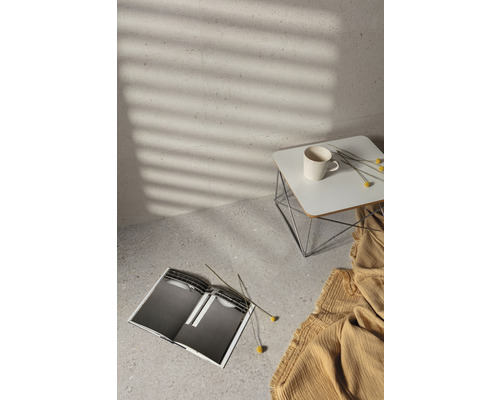 Heller Raum mit Fliesenboden, Beistelltisch, Tasse, Buch und Dekoration