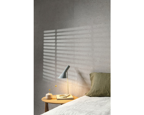 Chambre avec carrelage mural gris, table de chevet et lampe