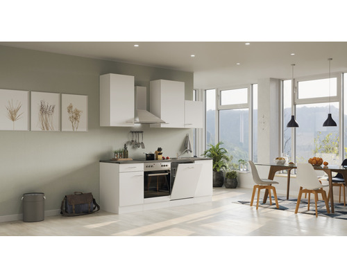 Cuisine moderne et lumineuse avec armoires blanches, table à manger et chaises dans une pièce spacieuse.