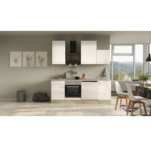 Cuisine intégrée lumineuse avec façades blanches, hotte aspirante et coin repas devant une fenêtre.