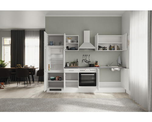 Cuisine compacte avec évier, cuisinière, four, hotte aspirante et réfrigérateur dans une pièce lumineuse.