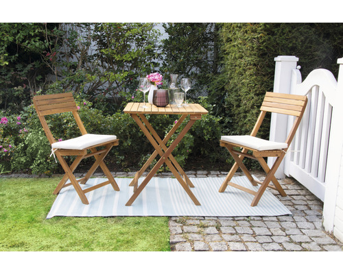 Scène de jardin avec table en bois et deux chaises avec coussins d''assise sur une pelouse