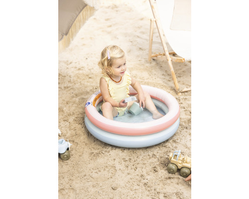 Enfant assis dans une pataugeoire gonflable sur la plage