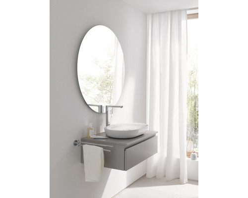 Badezimmer mit ovalem Spiegel, Waschbecken, Armatur, Handtuchhalter und Unterschrank
