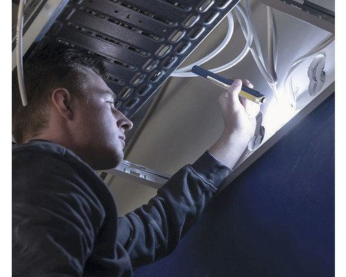 Un homme inspecte un évier avec une lampe d''inspection