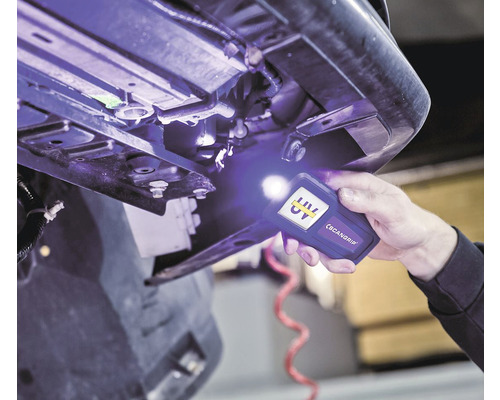 Une personne utilise une lampe de poche UV pour inspecter un véhicule.