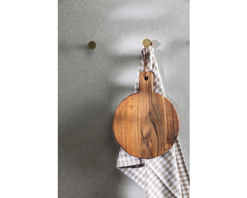 Rundes Holzschneidebrett hängt an einem Haken über einem Küchentuch