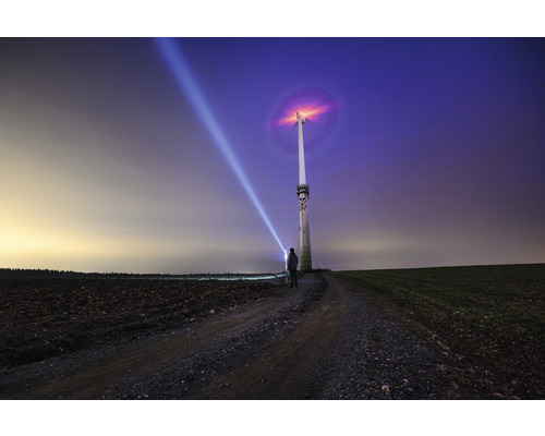 Windkraftanlage mit Person und Lichtstrahl in der Landschaft