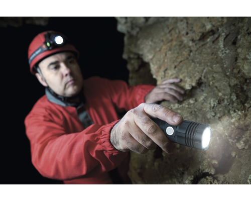 Homme avec lampe frontale et lampe de poche dans une grotte