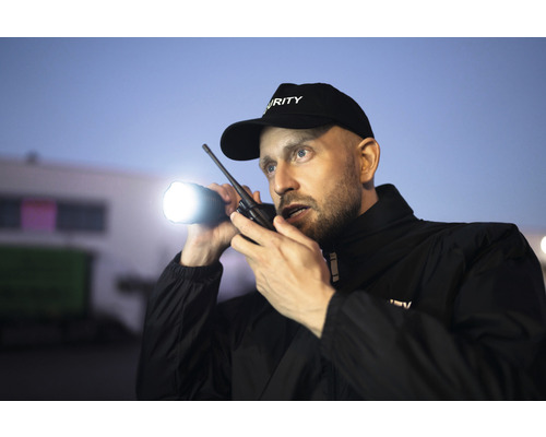 Un agent de sécurité avec une lampe de poche et un talkie-walkie