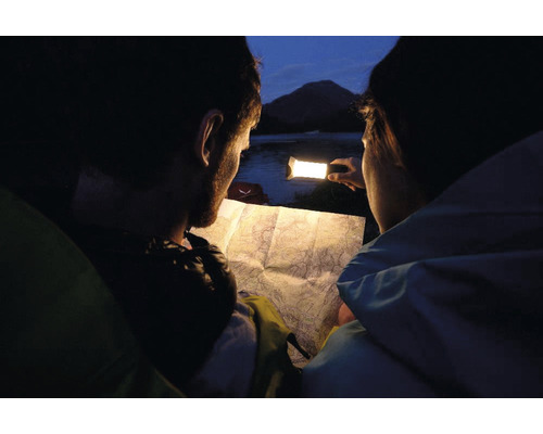 Deux personnes regardent une carte avec une lampe dans l''obscurité.