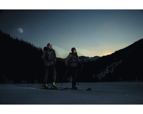 Deux personnes avec lampes frontales et skis dans la neige dans un paysage nocturne.
