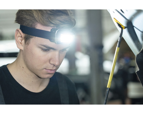 Homme avec lampe frontale réparant une voiture