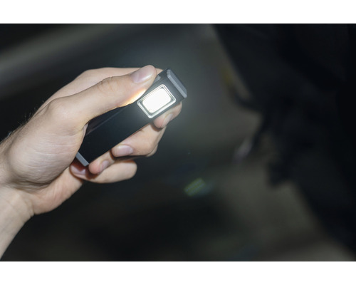 Une main tient une lampe de poche LED rectangulaire qui brille.