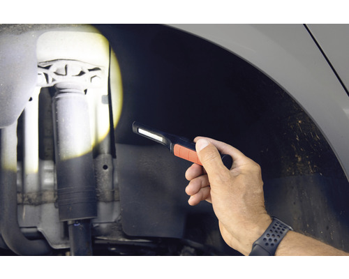 Une main tient une lampe d''inspection pour vérifier le véhicule.